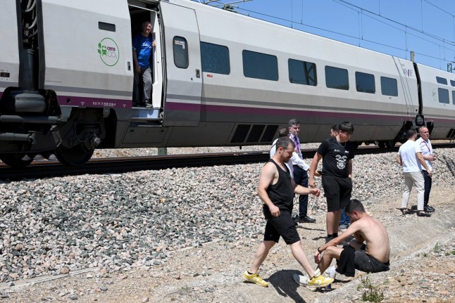 Passengers stand next to a stopped RENFE high-speed AVE train near Cordoba on April 28, 2025, during a massive power cut affecting the entire Iberian peninsula and the south of France. A "massive" power cut late on April 28, 2025 morning affected the whole of the Iberian peninsula and part of France, according to Portuguese electricity network operator REN. (Photo by JAVIER SORIANO / AFP) (Photo by JAVIER SORIANO/AFP via Getty Images)