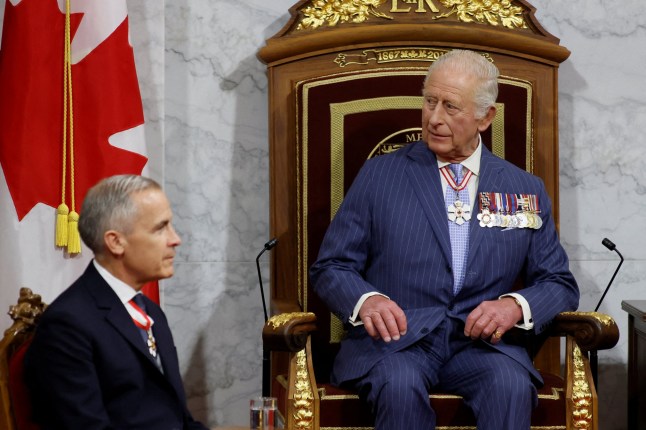 Canadian Prime Minister Mark Carney sits next to Britain's King Charles at the Senate of Canada Building in Ottawa, Ontario, Canada May 27, 2025. REUTERS/Blair Gable/Pool REFILE - CORRECTING ACTION FROM "STAND" TO "SITS".
