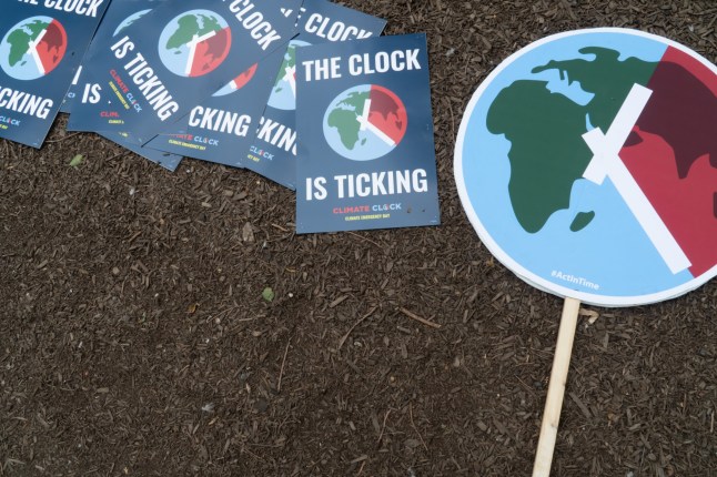 Several signs that read "The Clock is Ticking" lie in pile on the ground, next to a larger one, Climate Emergency Day, Union Square, New York City, July 22, 2024. All feature a graphic design with an image of part of the earth as a clockface, complete with hour and minute hands. In small print, the larger sign includes the message "#ActInTime". The text is a reminder that many believe humanity has only a few more years to make drastic changes to prevent average global temperatures from rising an additional 1.5 degrees Celsius. (Photo by: John Senter/UCG/Universal Images Group via Getty Images)